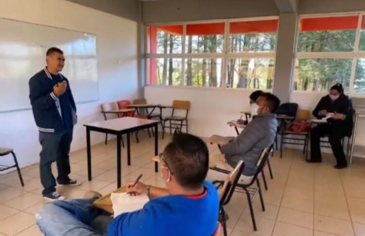 Estudiante presentando en aula con otros alumnos, aula moderna con vista a la naturaleza, ambiente de aprendizaje tranquilo y innovador.