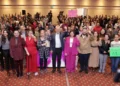 Celebración y apoyo en evento de mujeres, con oradores y participantes uniendo fuerzas.