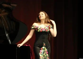 Jazzwoman tocando piano en escenario con vestido floral elegante.