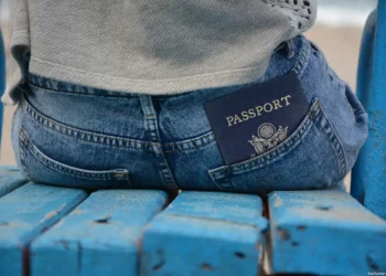 1. Pasaporte en el bolsillo trasero de jeans en banco de madera azul.