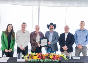 Reconocimiento empresarial presentado en evento formal con ejecutivos y un representante con sombrero cowboy.