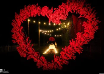 Amor en forma de corazón con luces y flores en evento nocturno romántico.