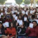 Aprendizaje masivo de estudiantes en un evento al aire libre con certificados en mano.