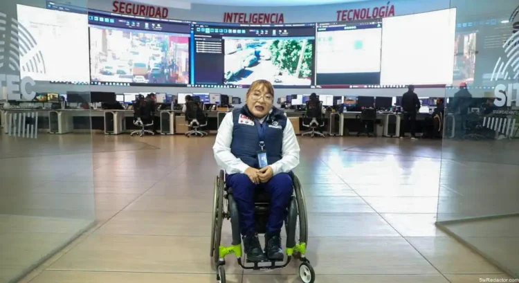 Personaje en silla de ruedas en centro de control de seguridad con pantallas de tecnología avanzada en fondo.