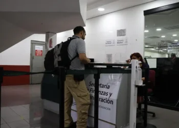 Agente en ventanilla de atención en oficina gubernamental en interior de edificio público.