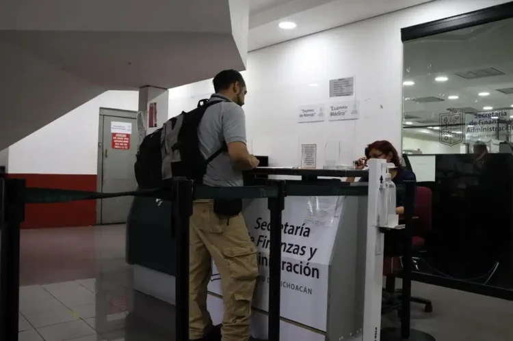 Agente en ventanilla de atención en oficina gubernamental en interior de edificio público.