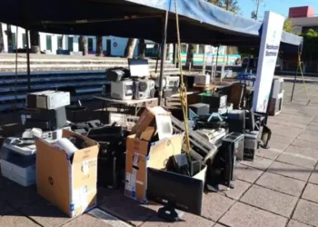 Basurero con computadoras y electrónicos usados en una plaza pública.