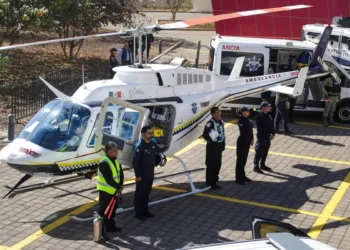 Helicóptero de emergencia con personal de rescate y ambulancia en escena.