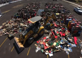 Basura y reciclaje de electrónicos en un estacionamiento, con maquinaria de recolección en acción.