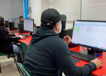 Aprendizaje en aula de informática con estudiantes usando computadoras y software de gestión.