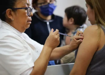 Vacunación contra COVID-19 en un centro de salud con personal médico y pacientes presentes.